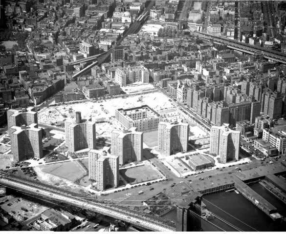 This 1951 aerial view of the Two Bridges section of the Lower East Side shows the construction of the Governor Alfred E. Smith Houses between Madison (top of construction site), Catherine (right), and South streets (bottom). The Brooklyn Bridge can be seen in the foreground; the arch and colonnade for the Manhattan Bridge can be seen in the top right-center of the photo. NYPL Digital Collections
﻿