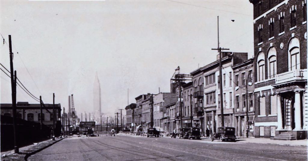 In this photo of Borden Avenue taken in 1934, the Y.M.C.A. building on the right looks all boarded up. Construction on the Midtown Tunnel began in 1936, and by 1939, all of these buildings had been demolished. Today, the ventilation building for the tunnel stands on this site. NYPL Digital Collections
