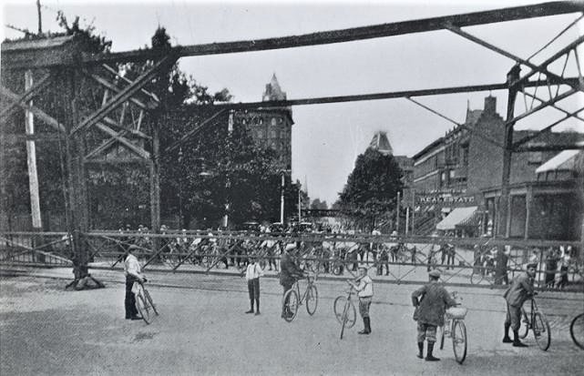Wheelmen wait impatiently at the barriers for the busy grade crossing on Bedford Avenue (about 1899). 
