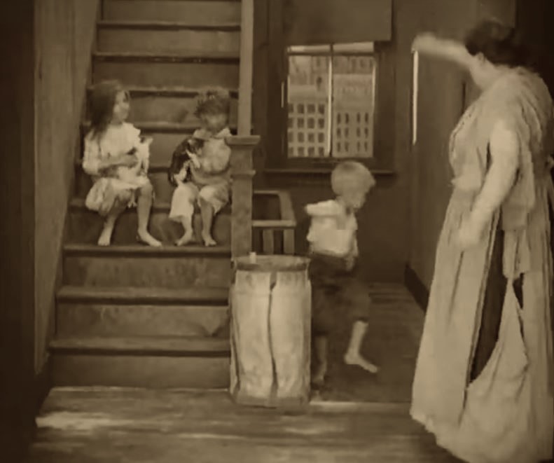 A few minutes into the film, several more cats appear on the steps with some children inside a dingy tenement building.  