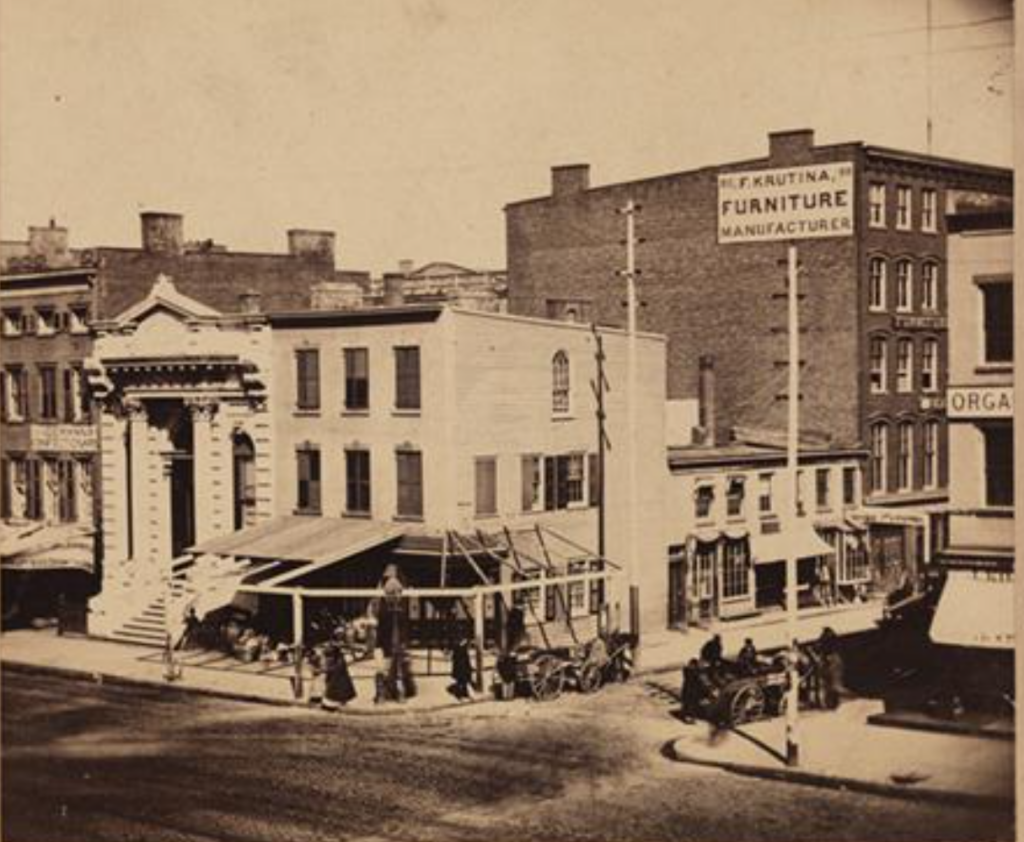 The pianoforte store at 286 Bowery is just barely visible on the far right of this 1864 photograph of the Bowery and East Houston Street. At this time, it was still a two-story building. NYPL Digital Collections